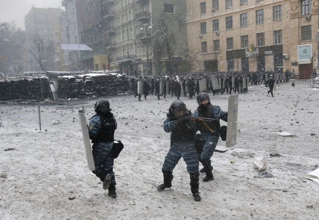 Paramilitary forces firing a shotgun at armed insurgents - just a police officer having a "clash" with some rowdy protesters.