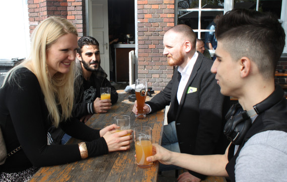 In this May 1, 2016 photo Cindy Spieker, Ahmed Haj Ali, Paul Spieker and Abdul Wahab, from left, sit around a table in Berlin. The group met through a website called 'Let's integrate!' that sets dates between refugees and locals in Berlin. (AP Photo/Jona Kallgren)